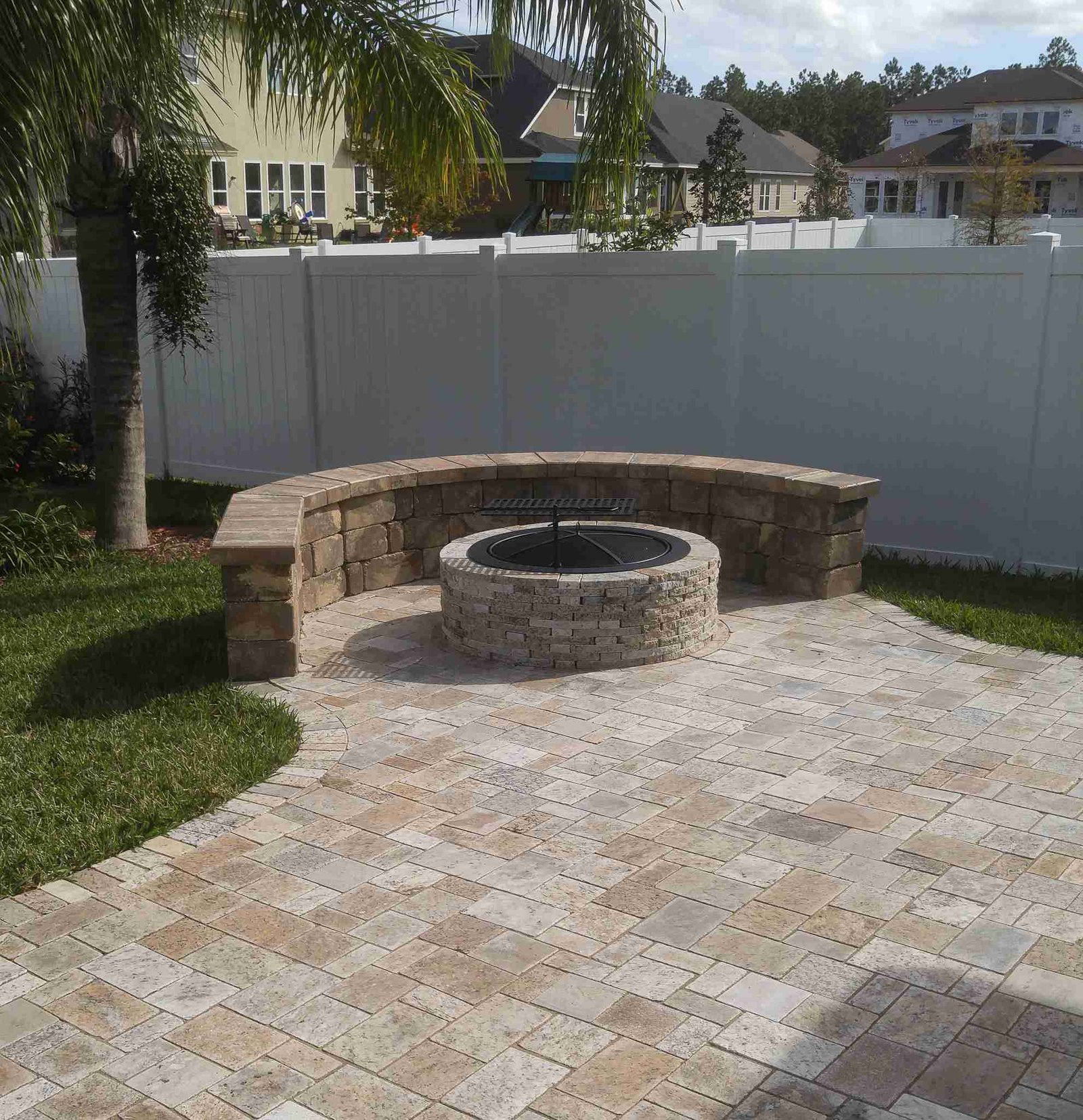 Curved stone fire pit with sitting wall on paver patio